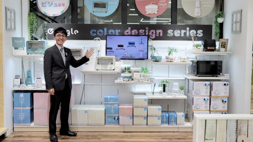 家電eangleの前で手を挙げて案内をする開発の木村さん